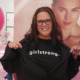 Girlstrong fashion: Young woman with long dark hair and dark-framed glasses wears black t-shirt with "Girlstrong" in white letters on chest