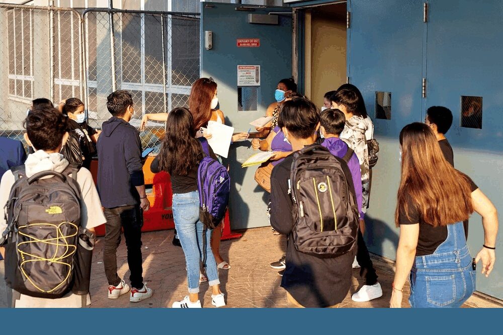 NYC network of school serving immigrants preparing for Trump: group of students, some in masks, entering school building