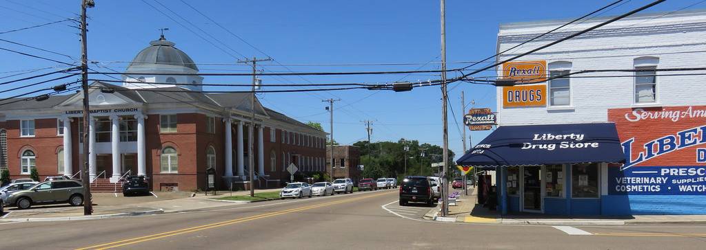 Amite school segregation academies: Downtown in Liberty, Mississippi, an intersections with low-rise buildings and one multi-story red brick building with dome roof to the left