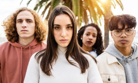 High school drop-outs: Close-up of four mixed ethnicity young adults - 2 women and two men - stare into camera with serious faces.