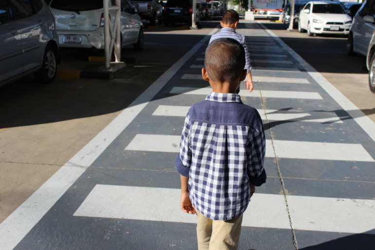 Curriculum fidelity k-12: Young boys walk single file in white striped crosswalk