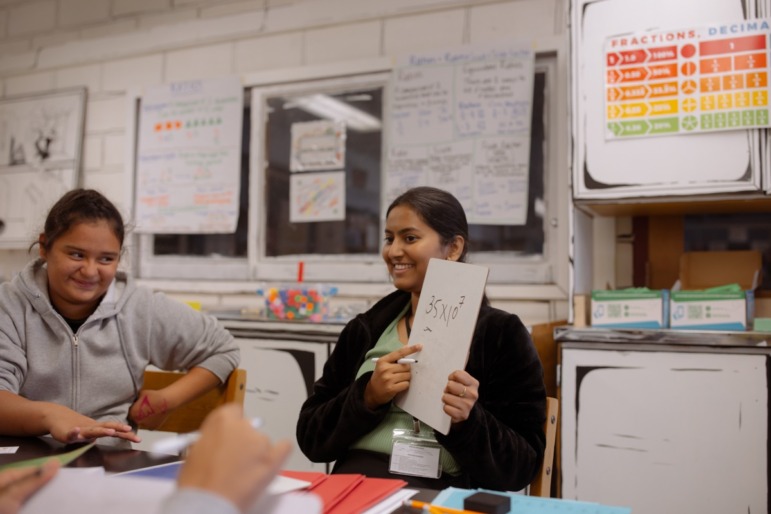 Maryland push to scale up high dosage math tutoring: female teacher holds up white board with math on it 