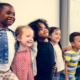 Childcare: several young children stand in a line with arms around each others shoulders