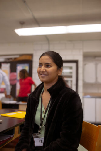 Maryland push to scale up high dosage math tutoring: Woman with dark hair pulled back in black sweater stands in classroom