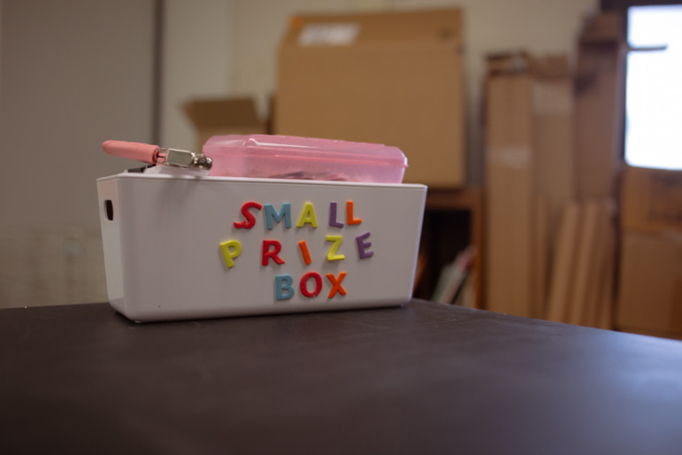 Maryland push to scale up high dosage math tutoring: Small white box with multi-color lettering "Small Prize Box" sits on dark tabletop