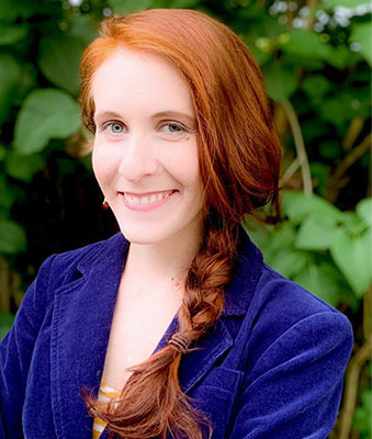 Migrant children: Headshot redhead woman in dark blue suit jacket