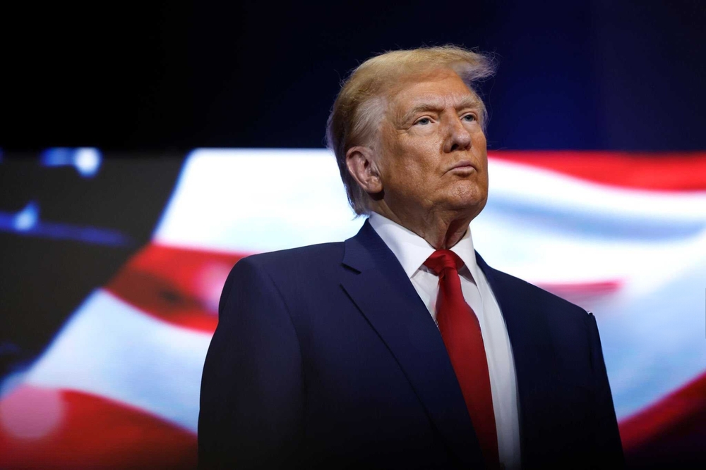 9 education topics for 2025: President Trup in navy suit with red tie and white shirt stands in front of large American flag