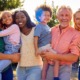 Generational empathy: 2 senior adults, 2 adults in their thirties, and two children being held by adults, stand in a line smiling into camera.