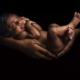 Children face unique vulnerabilities to environmental hazards at every stage of life: black infant being held by mothers arms against black background