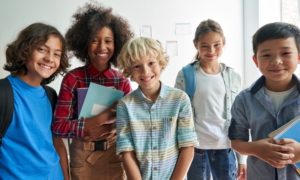 Thriving youth, child health grant: Multi-ethnic group of 5 children ages elementary to middle shool standing together smiling into camera
