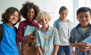 Thriving youth, child health grant: Multi-ethnic group of 5 children ages elementary to middle shool standing together smiling into camera