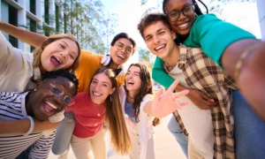 Thriving youth: Multi-ethnic group of 7 teenagers standing together laughing and smiling into camera