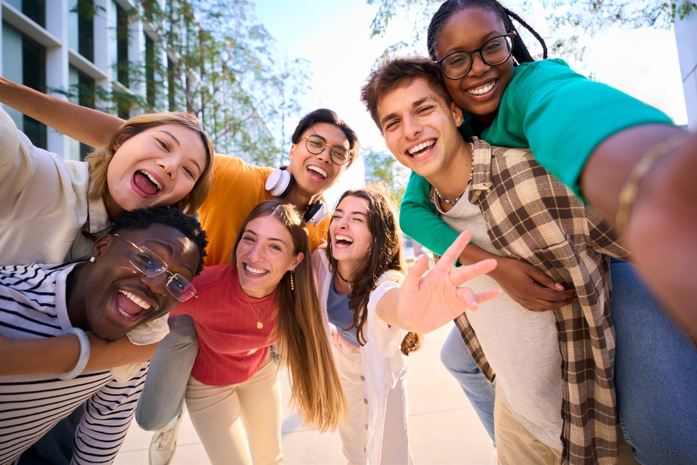Thriving youth: Multi-ethnic group of 7 teenagers standing together laughing and smiling into camera