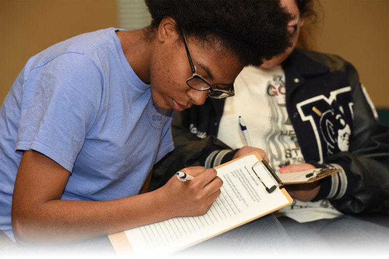 Professional development: Young black woman filling out form on clipboard