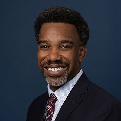 Podcast juvenile justice: Headshot Black man with black hair in dark suit and white shirt with dark tie