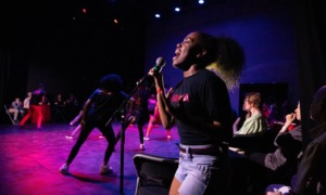 Well-being and well-becoming through the arts_A picture of mattering for youth of color: young black woman singing on stage passionately