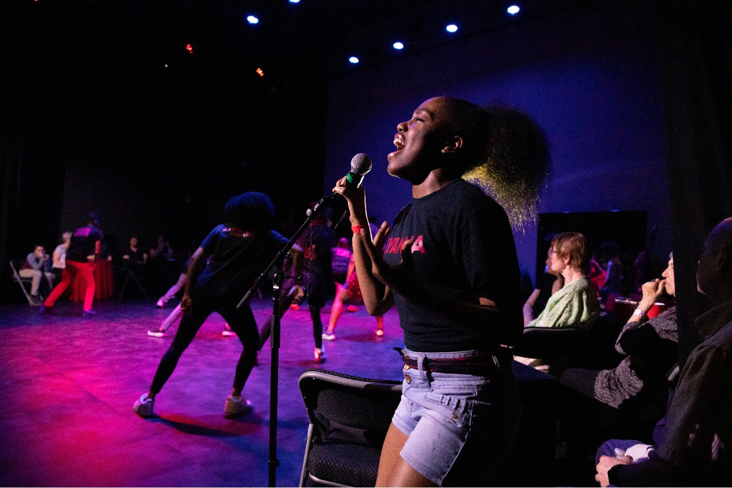 Well-being and well-becoming through the arts_A picture of mattering for youth of color: young black woman singing on stage passionately