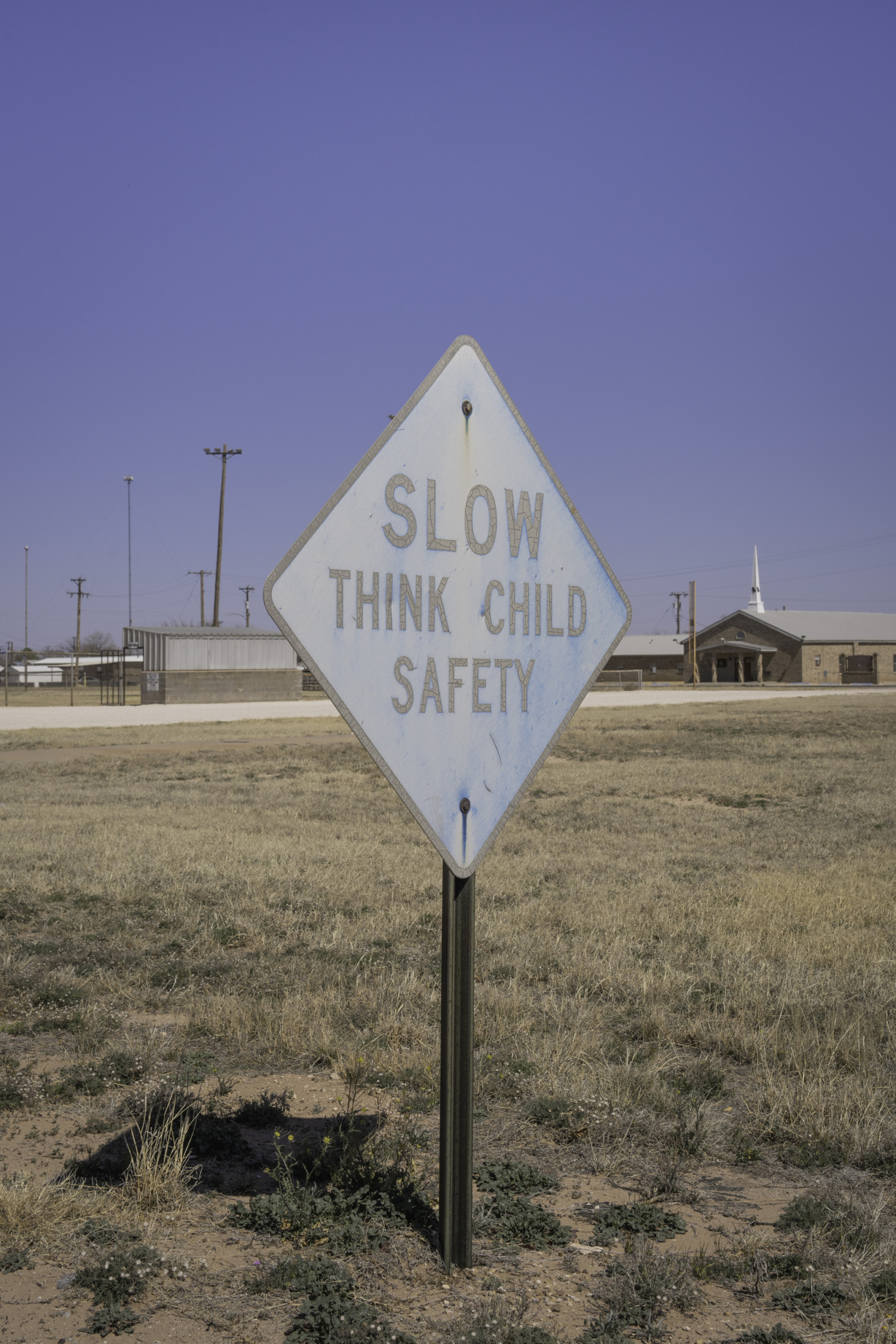 Whooping Cough & Measles outbreak: Old. faded yellow road sign with black text in all capitals "Slow Think Child Safety"