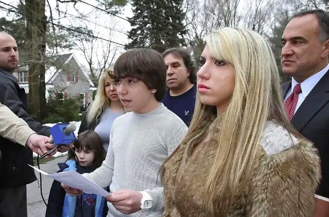 Student surveillance documentary "Sky High": Teen boy with dark hair stands outside next to woman with long blonde hair with several microphones held by adults facing them are in their faces