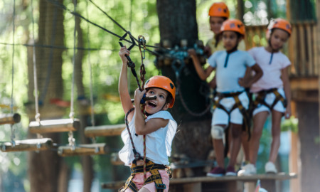 Camp Fire outdoor program interview: 4 children, playing on rope obstacle course. One child swinging on rope.