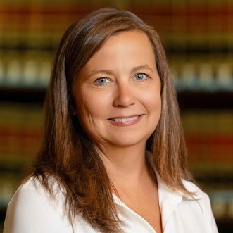 US Supreme Court religious charter school case:: Headshot woman with long blonde hair in white blouse in front of book shelves filled with red and black bound law books
