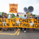 climate decision-making, Climate change: youth at street protest with many signs amd large deep yellow banner with black text, "We are the ones we've been waiting for."
