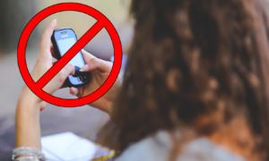 Cell phoe ban: Cell phone in hands of woman with red prohibited circle symbol over phone
