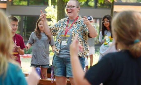 Camp Fire LGBTQ & Trans inclusion: Adult leads activity with group of campers standing around them in a circle