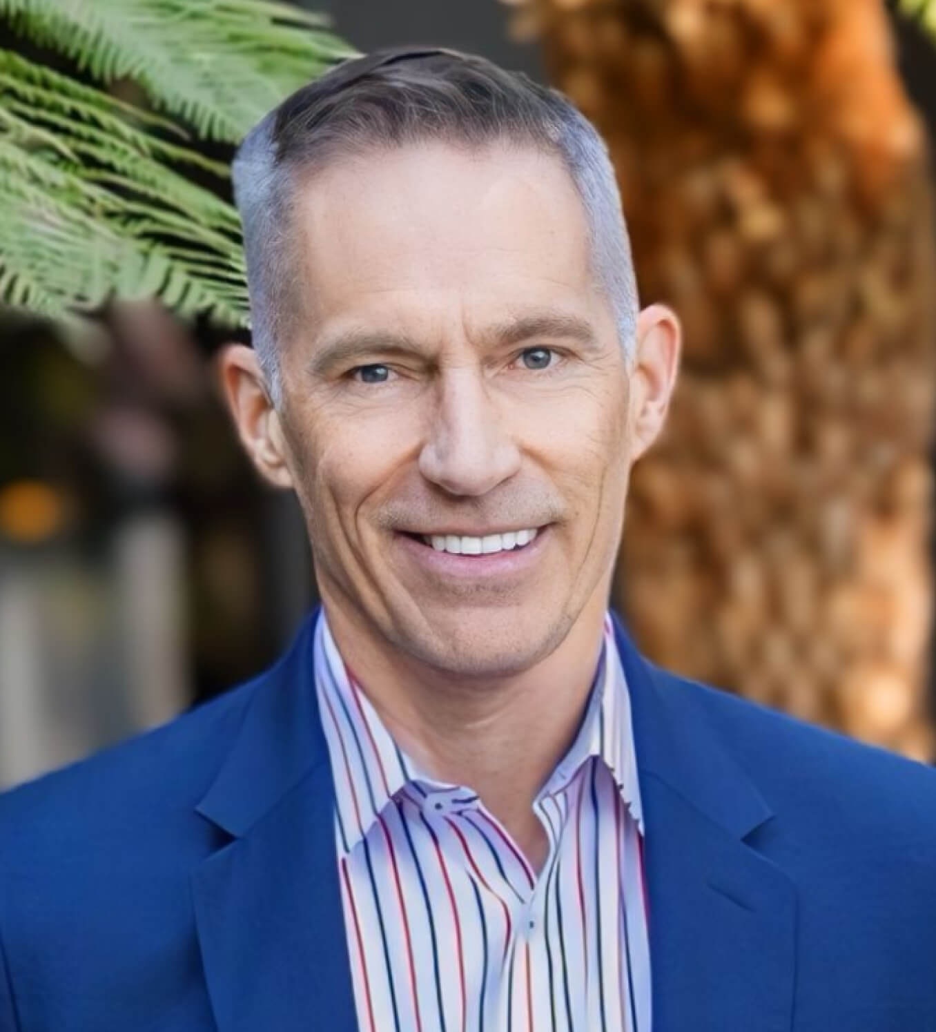 Mark Cloutier headshot: white man in blazer and striped shirt smiling outdoors