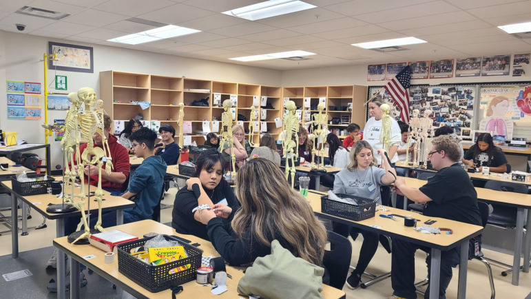 High school diploma pathways: Stuents sit at desks in pairs practicing med tech lab tests on each other
