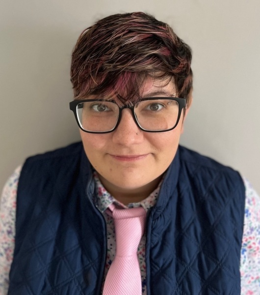 Reimagining aging out of foster care: woman with short brown hair and black-rimmed glasses wearing a vest