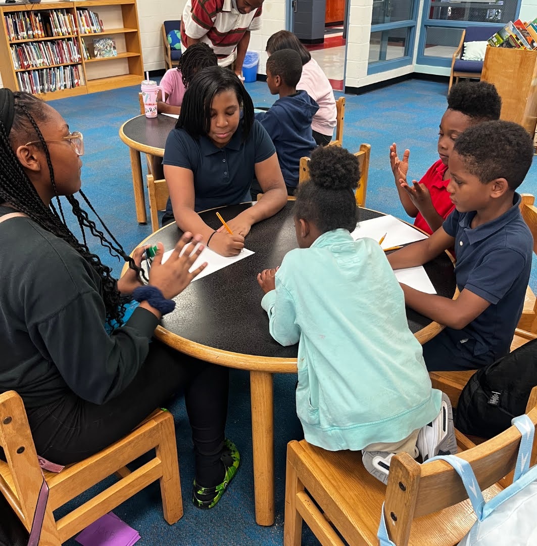 QA_how service learning done well changes lives: group of young black students being helped by older students at table
