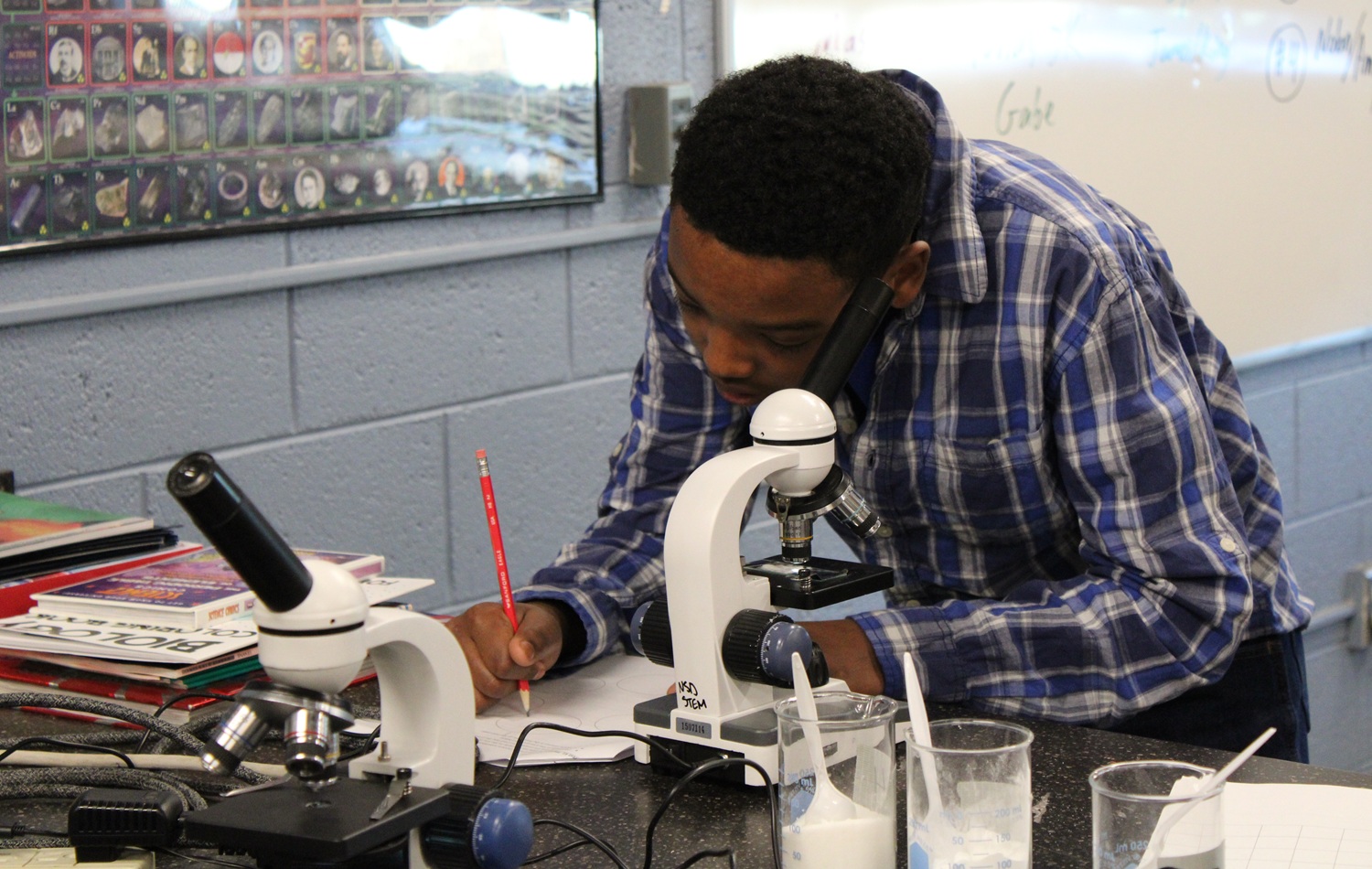Reimagining support for learning differences_What parents find in learner-centered environments: black males student in flannel shirt works with microscope