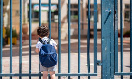 Uniting in defense of the ecosystem, federal education funding freeze: Kid with school backpack standing at locked gate