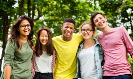 We dont have to choose which adolescent development challenge to tackle: group of five diverse youth smiling in outdoor setting