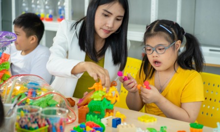 children with disabilities grants: woman in white blazer helps young children with disabilities