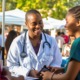 community and public health grants: smiling black female doctor talks to people at outdoor community health event