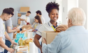 Human services, basic needs, well-being grants, Carolinas grants: smiling young black woman giving older white man box of necessities