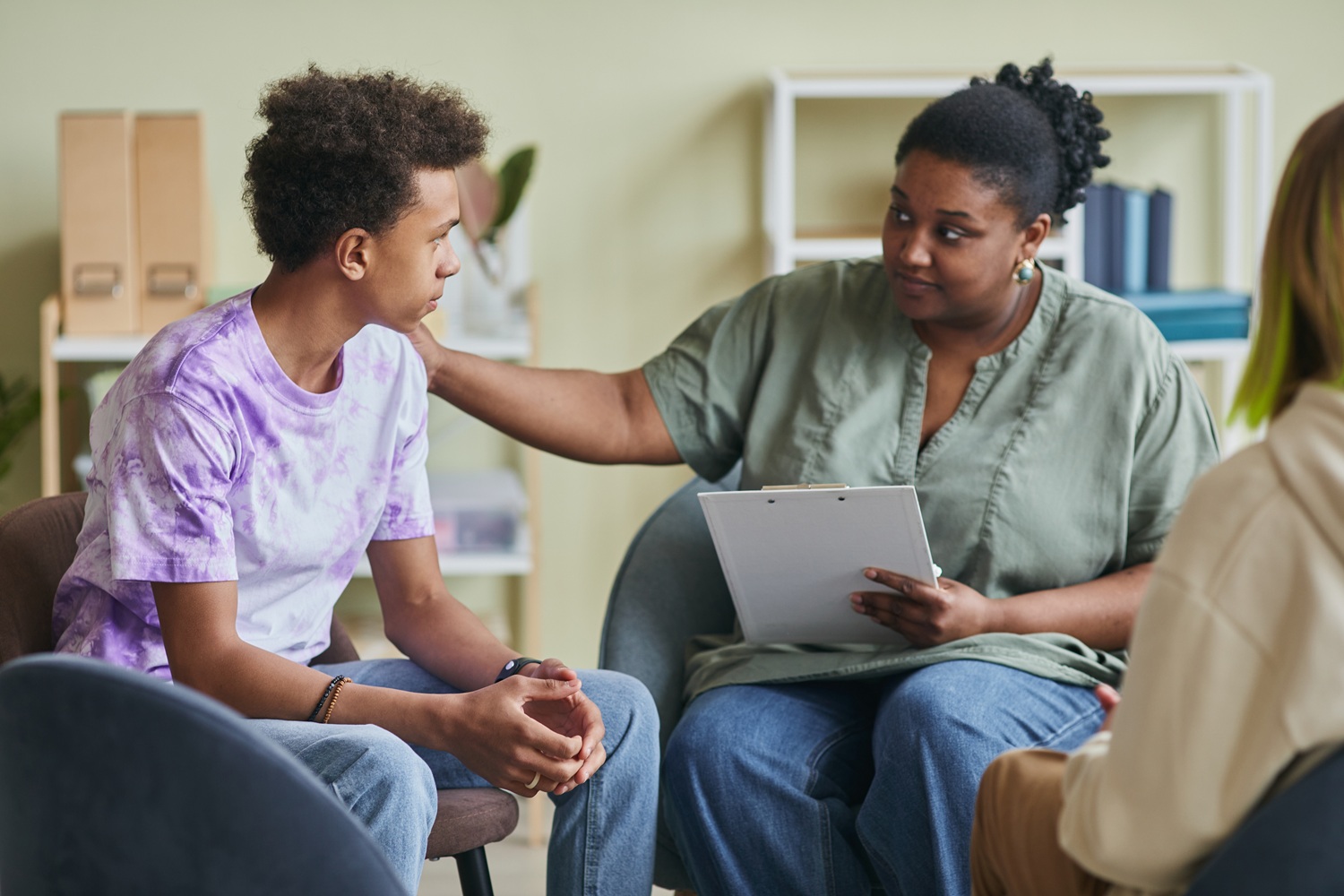 Youth mental health is personal_Our solutions need to be systemic: black female therapist comforts black male student during therapy