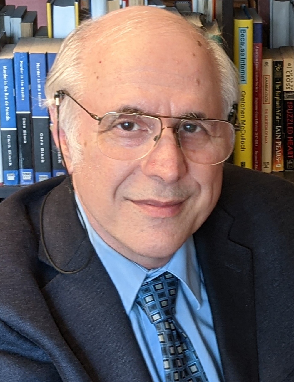 Richard Wexler headshot: older white man in glasses and suit in front of bookshelf