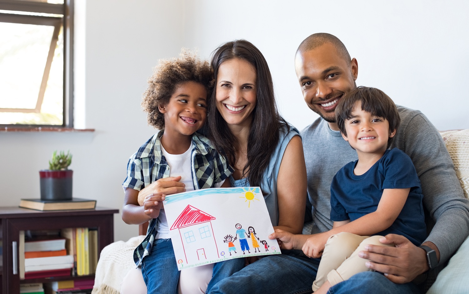 Sieze the foster care insurance crisis as an opportunity to curb foster care: happy interracial family smiling and holding child's drawing of home and family