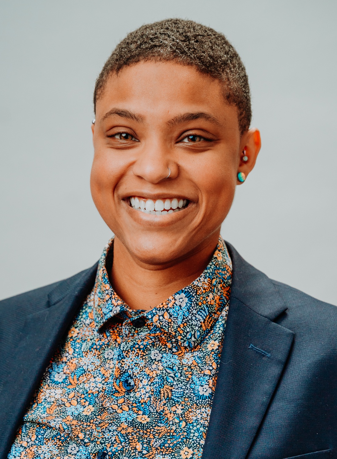 Shelby Payne-Drayton headshot: smiling black woman with short hair in blazer and colorful shirt
