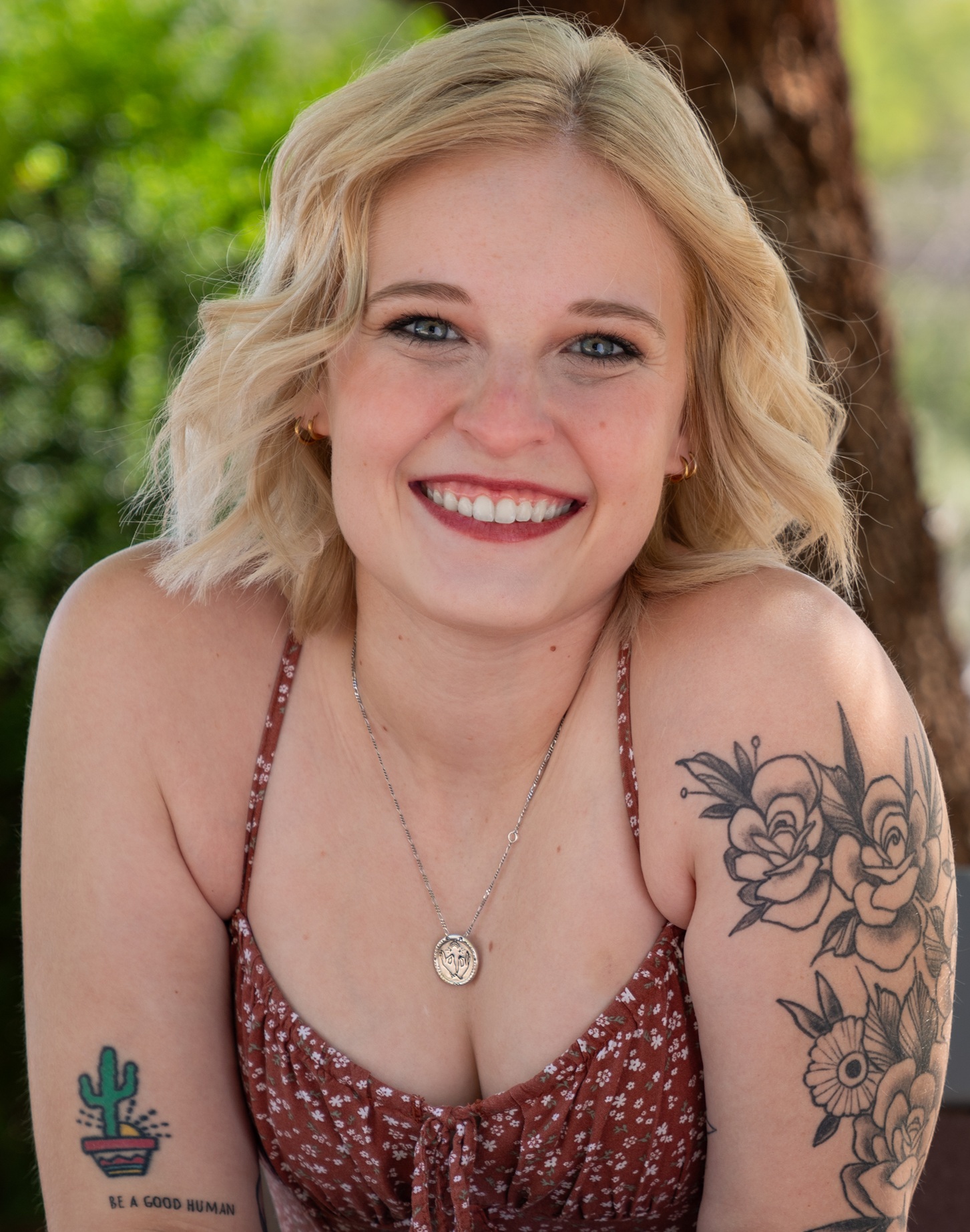 Healing power of camp_Tayler Wiese headshot: young white woman with blonde hair and tattoos smiling in outdoor setting