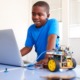 Afterschool STEM education: young black boy working on laptop connected to robotic wheel device