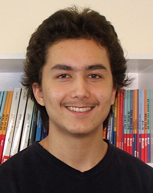 Ean Soh headshot: young male student with dark hair standing in front of bookshelf