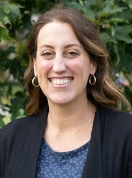 Erica Van Steenis headshot: smiling white woman with long dark hair outdoors