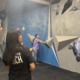 From athlete to youth sports coach_A new ascent_feature: two young women watch on as another swings legs out from climbing wall