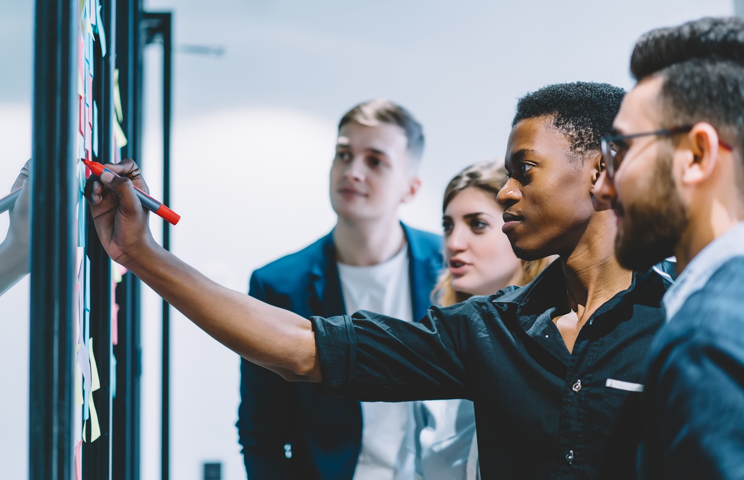 From developmental relationships to opportunities_social capital mobilization_feature: black male youth confidently writes on idea wall in front of peers