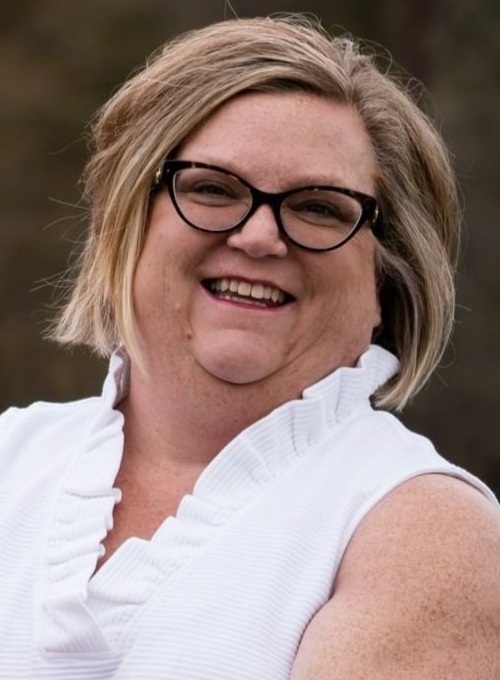 Gaile Osborne headshot: white woman with black-rimmed glasses and white shirt smiling outside