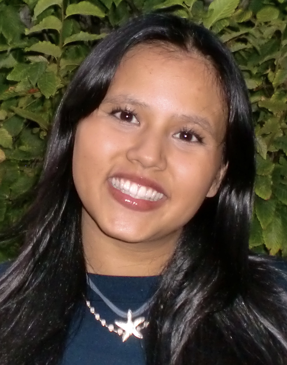 Mei Mei Loh headshot: young Asian woman smiling in front of greenery
